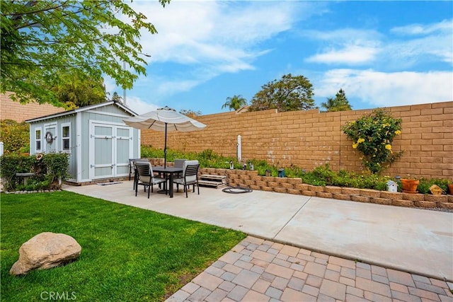 view of patio / terrace with an outbuilding, fence, and a storage unit