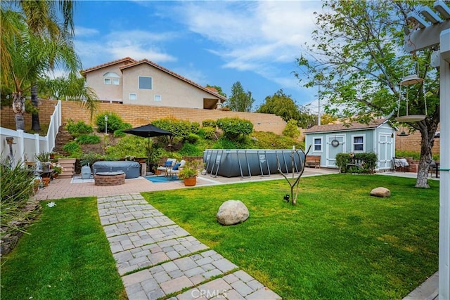 view of yard with a patio, a jacuzzi, an outdoor structure, a fenced backyard, and a fenced in pool