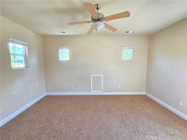 carpeted empty room featuring a healthy amount of sunlight and visible vents