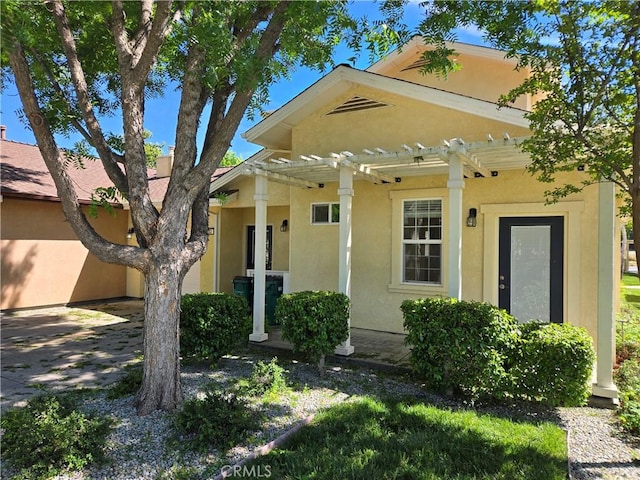view of front facade with a pergola and stucco siding