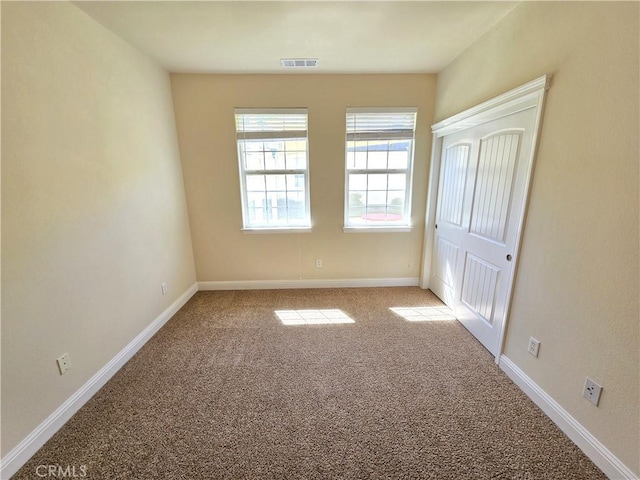 unfurnished bedroom with carpet flooring, baseboards, a closet, and visible vents