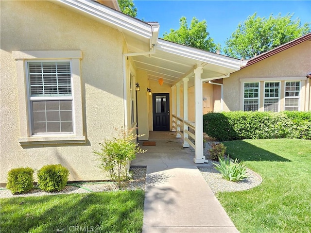 view of exterior entry featuring a yard and stucco siding