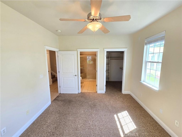unfurnished bedroom featuring ensuite bathroom, a closet, carpet floors, a walk in closet, and baseboards