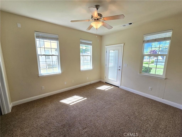 carpeted empty room with plenty of natural light, visible vents, baseboards, and a ceiling fan