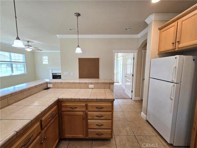 kitchen with freestanding refrigerator, tile countertops, and crown molding