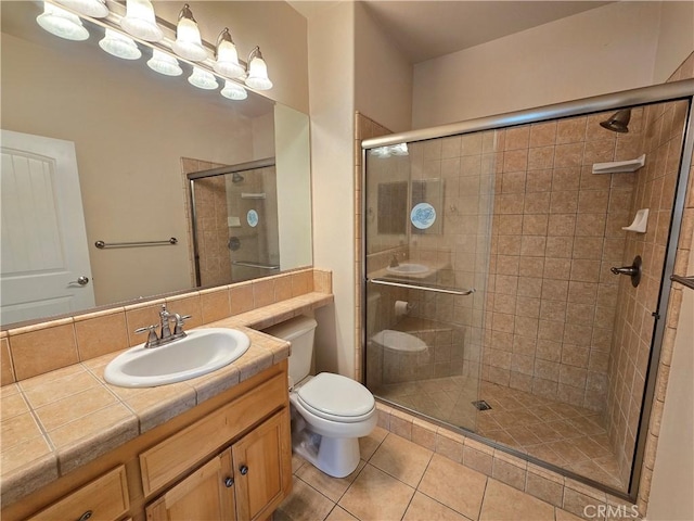 full bath featuring a shower stall, tile patterned floors, vanity, and toilet