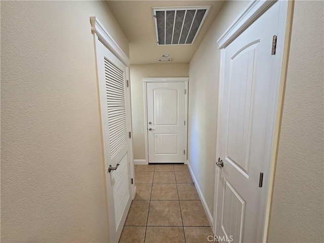 corridor featuring light tile patterned floors, baseboards, and visible vents