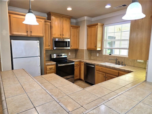 kitchen featuring ornamental molding, a sink, backsplash, tile counters, and appliances with stainless steel finishes