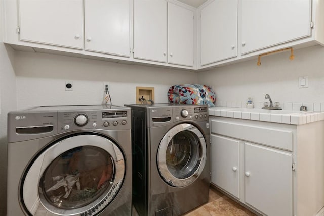 clothes washing area featuring a sink, washing machine and dryer, and cabinet space