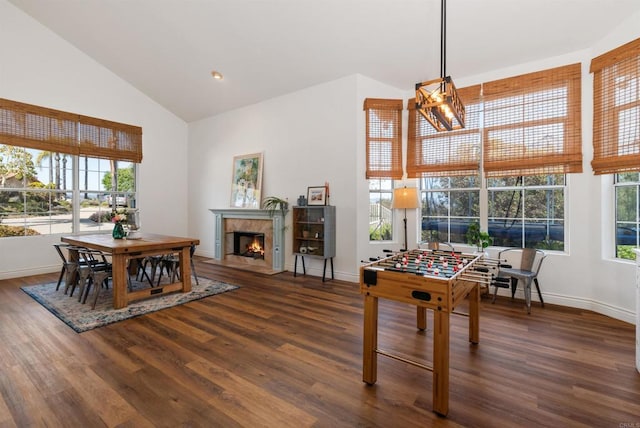 game room featuring baseboards, a fireplace with flush hearth, high vaulted ceiling, and wood finished floors