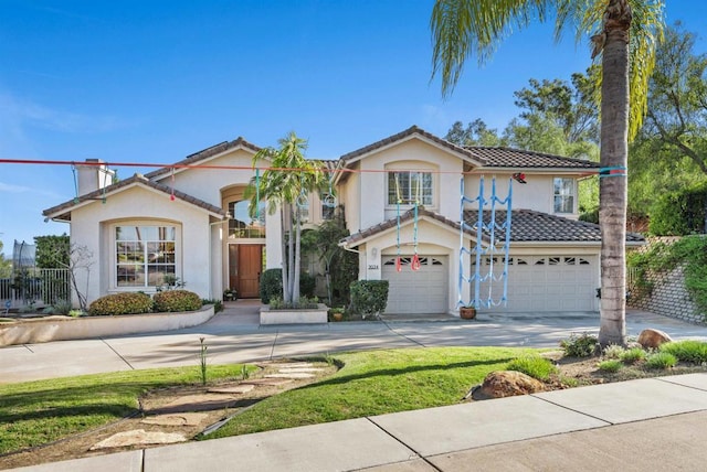 mediterranean / spanish house with an attached garage, driveway, a tile roof, stucco siding, and a chimney