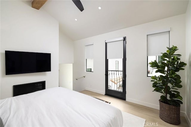 bedroom featuring lofted ceiling, multiple windows, baseboards, and wood finished floors