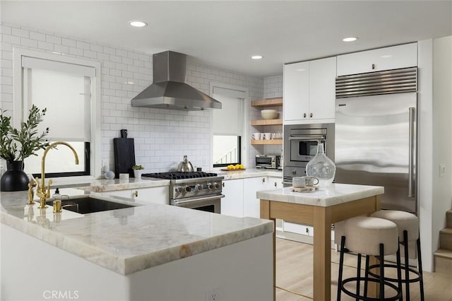 kitchen with a sink, wall chimney range hood, open shelves, white cabinetry, and high end appliances
