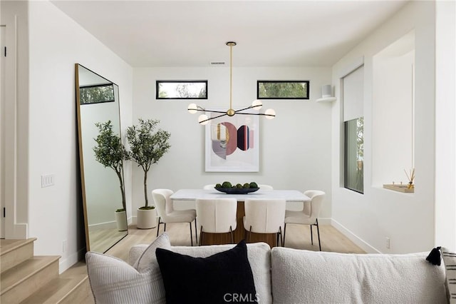 dining area featuring an inviting chandelier, a wealth of natural light, stairs, and light wood-style floors
