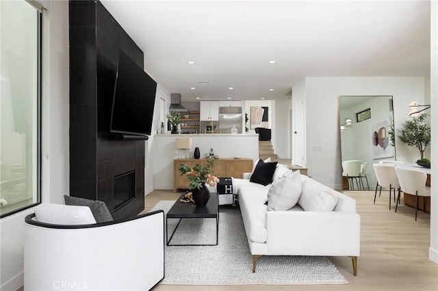 living room featuring light wood-type flooring, a fireplace, baseboards, and recessed lighting
