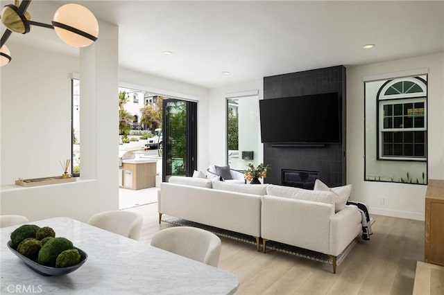 living room featuring a tiled fireplace, light wood-style flooring, and recessed lighting