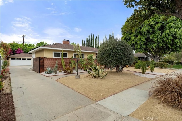 view of front of house featuring a chimney, brick siding, an outdoor structure, a garage, and stucco siding