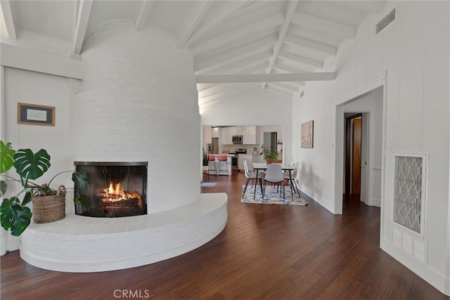 living room featuring visible vents, wood-type flooring, high vaulted ceiling, a fireplace, and beam ceiling