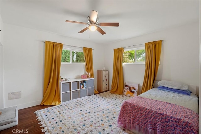bedroom with multiple windows, a ceiling fan, wood finished floors, and baseboards