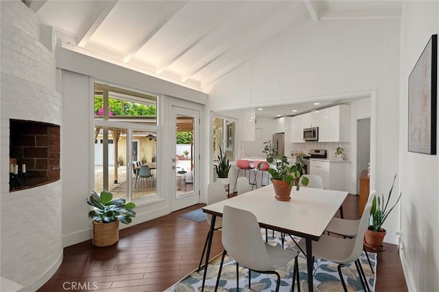 dining room with lofted ceiling with beams, a fireplace, and dark wood-style floors