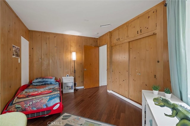 bedroom featuring dark wood-type flooring, visible vents, and wooden walls