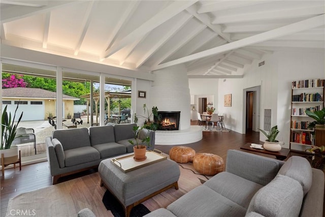living area with hardwood / wood-style floors, beam ceiling, a large fireplace, and high vaulted ceiling