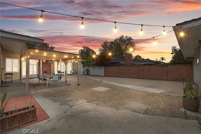 patio terrace at dusk featuring a fenced backyard