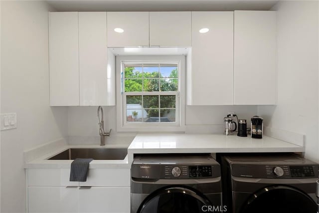 laundry room featuring cabinet space, washing machine and dryer, and a sink