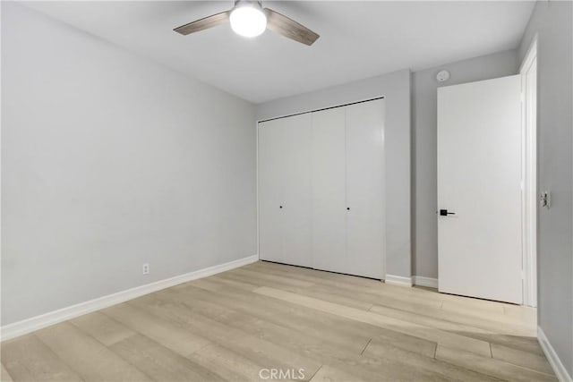 unfurnished bedroom featuring a closet, a ceiling fan, light wood-style flooring, and baseboards