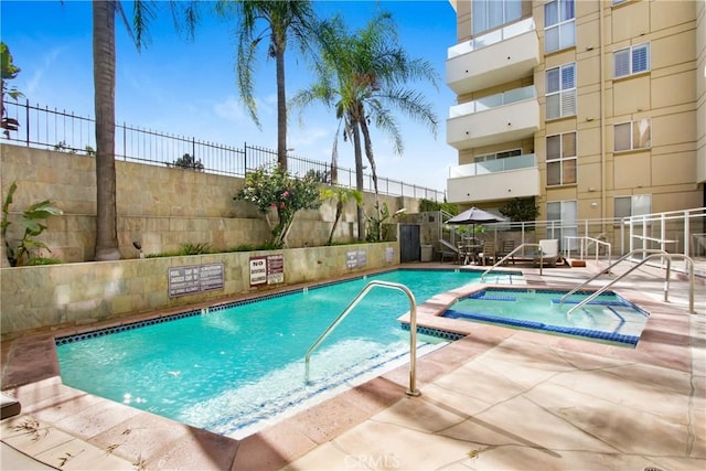 pool featuring a hot tub, fence, and a patio area