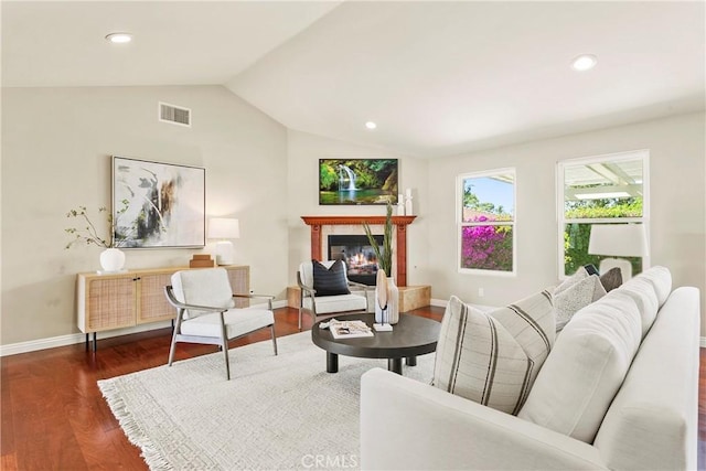 living room with lofted ceiling, visible vents, dark wood finished floors, baseboards, and a glass covered fireplace