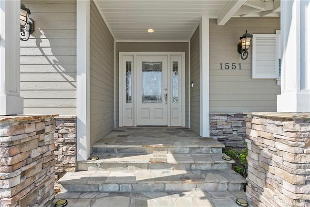 entrance to property featuring stone siding and covered porch