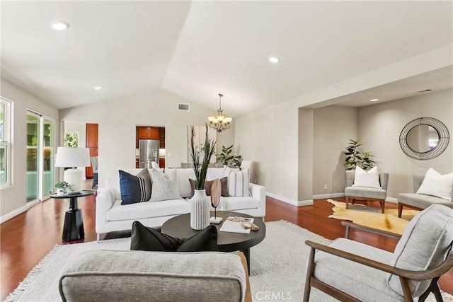 living area featuring a notable chandelier, baseboards, visible vents, vaulted ceiling, and wood finished floors