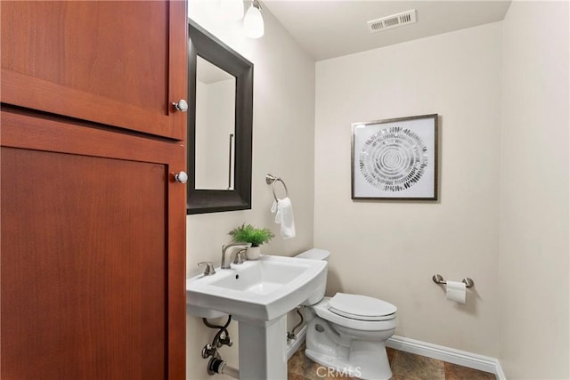half bathroom featuring a sink, toilet, baseboards, and visible vents