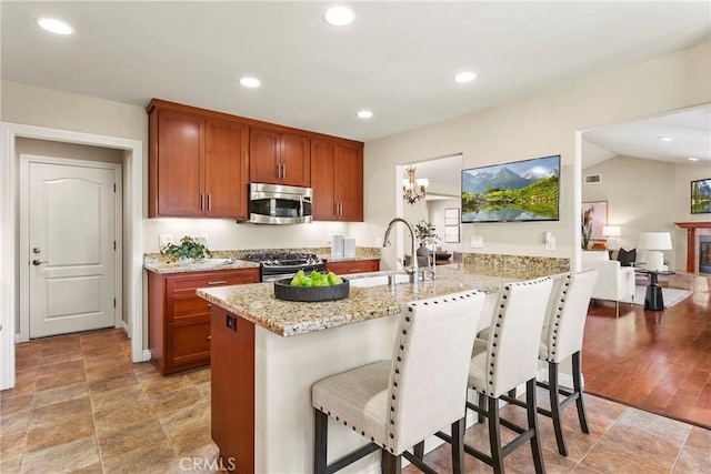 kitchen with light stone countertops, a breakfast bar area, a sink, a peninsula, and appliances with stainless steel finishes