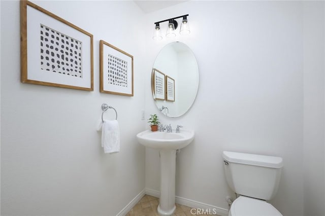 bathroom with toilet, baseboards, and a sink