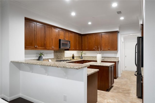 kitchen with a peninsula, stainless steel appliances, light stone counters, visible vents, and crown molding