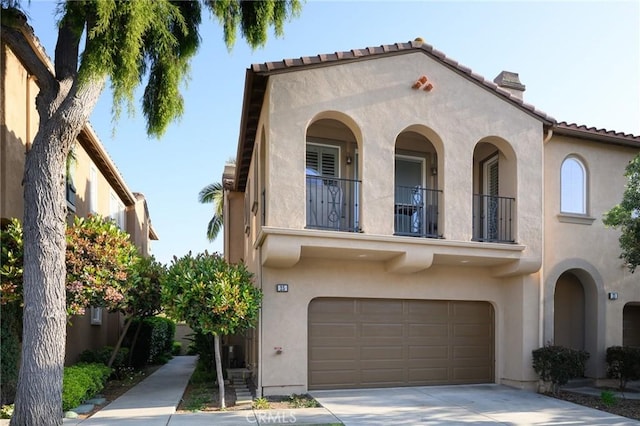 mediterranean / spanish home with a balcony, a tiled roof, a garage, stucco siding, and concrete driveway