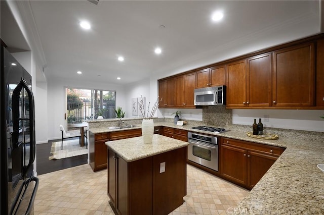 kitchen with a sink, a peninsula, light stone counters, crown molding, and appliances with stainless steel finishes