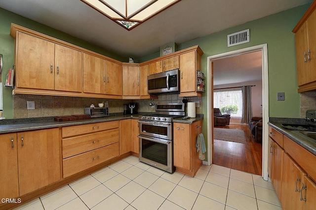 2030 Lomita Park Pl, Lomita, CA 90717 - kitchen featuring stainless steel appliances, dark countertops, decorative backsplash, and light tile patterned floors