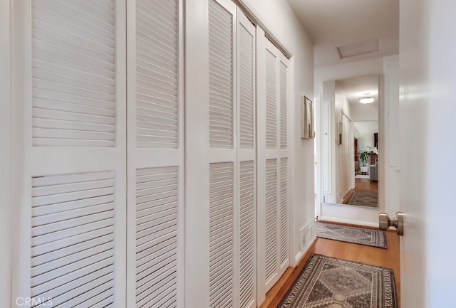 corridor with attic access and wood finished floors