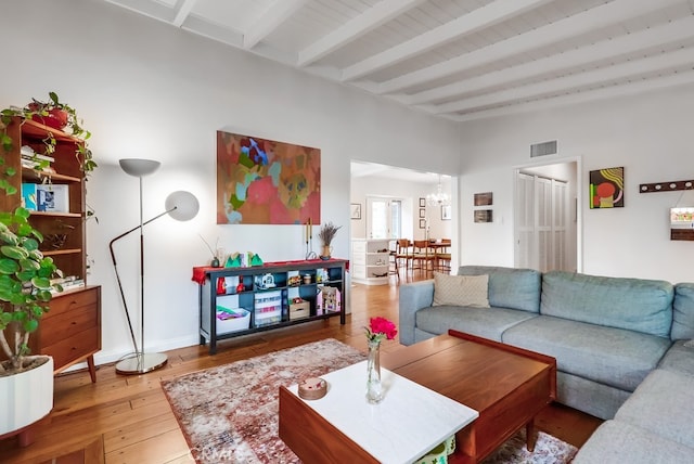 living area featuring baseboards, wood-type flooring, visible vents, a chandelier, and lofted ceiling with beams