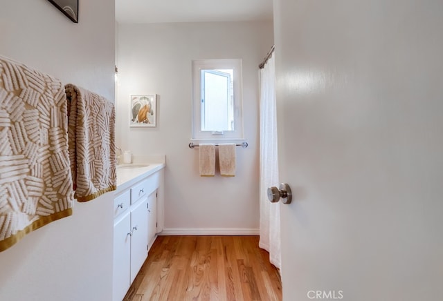 bathroom featuring baseboards, wood finished floors, and vanity