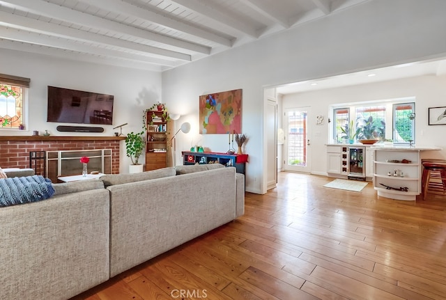living area featuring wine cooler, a wealth of natural light, a fireplace, and beam ceiling