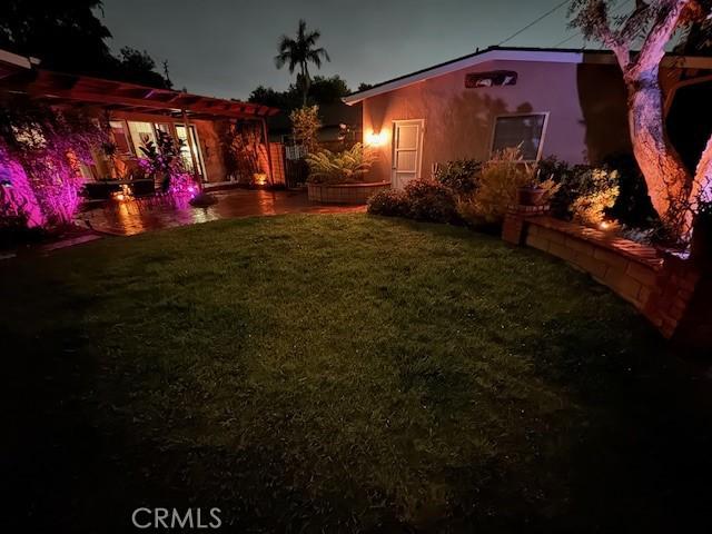yard at night with a patio area and a pergola