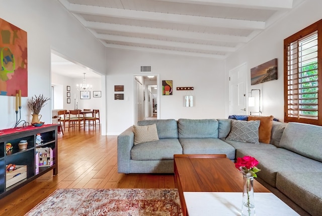 living room with lofted ceiling with beams, visible vents, an inviting chandelier, and wood-type flooring