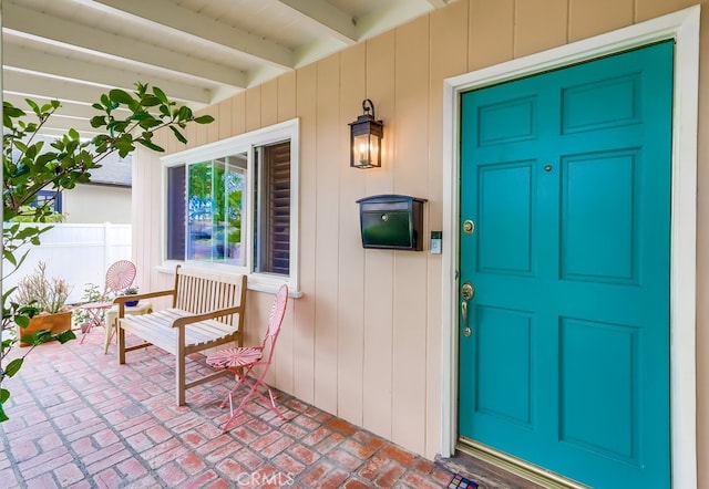 property entrance featuring covered porch and fence