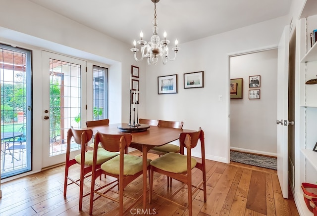 dining room with a chandelier, baseboards, and light wood-type flooring