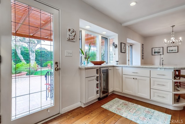 bathroom featuring a notable chandelier, hardwood / wood-style floors, a healthy amount of sunlight, and beverage cooler