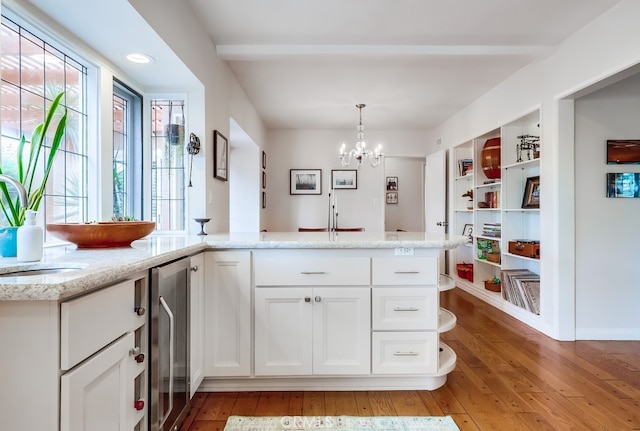 kitchen featuring a chandelier, white cabinetry, light wood-type flooring, and light stone counters